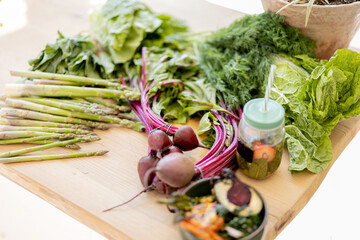 Top view on table full of fresh vegetables, fruits and greens. Healthy bowl and bottle with drink on a tray with lots of fresh food ingredients. Healthy vegan eating concept
