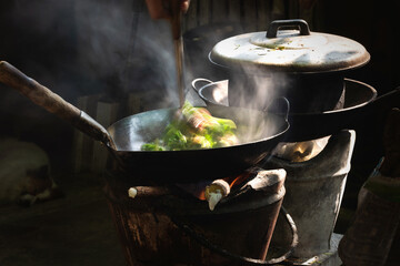 The man cooking vegetables in frying pan on vintage stove ,cooking with firewood