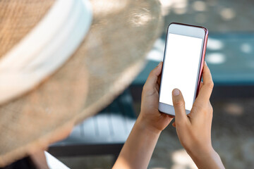 Close-up Asian woman hands holding and pointing on smartphone sunbathing by the sea. Online shopping, social, technology, communication. Clipping path on white screen isolated