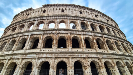 Fototapeta na wymiar Panoramic view on exterior facade of famous Colosseum (Coloseo) of city of Rome, Lazio, Italy, Europe. UNESCO World Heritage Site. Flavian Amphitheater of ancient Roman Empire. Concept tourism