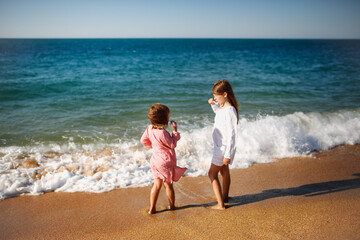 Children girls in capes from the sun brush their teeth on seashore, rest with tent and travel...