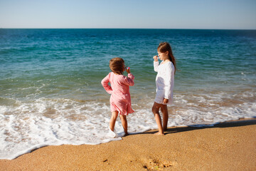 Children girls in capes from the sun brush their teeth on seashore, rest with tent and travel...