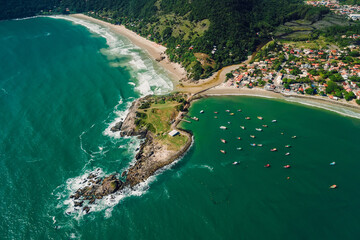 Coastline with rocky island, beach and ocean with waves and boats. Aerial view. Matadeiro Beach and Ponta das Campanhas