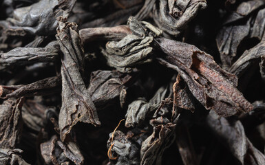 Dried black tea leaves as background.