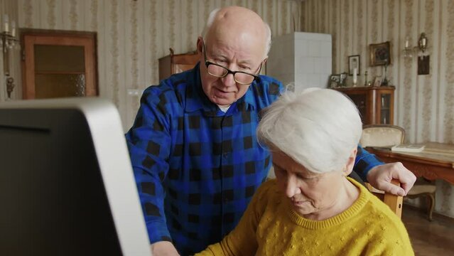 senior man helping his wife to use computer medium shot indoor modern seniority concept. High quality 4k footage
