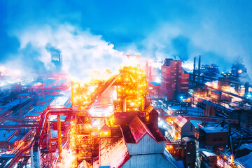 Night top view of a steel mill. Smog, smoke and flame from the chimneys. Metallurgical blast furnace in lights and smoke