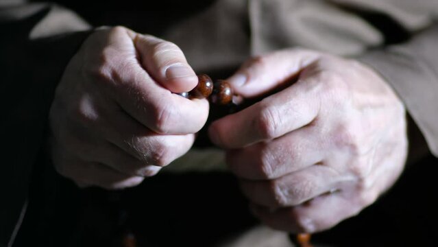 Close up video of the hands of a old monk are fingering the rosary.