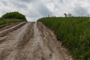 a country road and white cumulus clouds in a blue sky