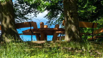 Sitzgruppe aus Holz auf einer Anhöhe mit Baum in einem Park