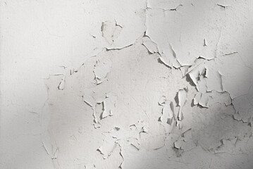 White cracked paint plaster on concrete wall, outdoors. Textured rough background