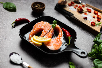 trout steak, a piece of fresh raw fish is in a frying pan. Next to the herbs and spices for cooking