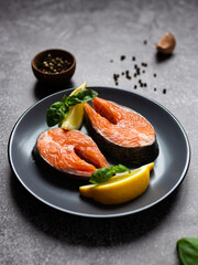 a piece of fresh raw trout lies on a gray plate. Next to the herbs and spices for cooking