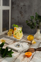 Ice-cold non-alcoholic lemon cocktail decorated with a sprig of mint on a light wooden background