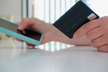 Woman with laptop and credit card at home . Online payment, digital banking. Online shopping concept, young woman hands holding mobile smart phone and credit card with laptop on table.