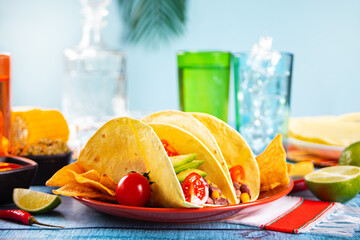 Traditional Mexican corn tacos with meat, vegetables, avocado, beans, salsa and nachos. Served with various sauces and drinks. Top view. Big family gatherings.