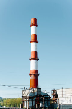 Industrial plant with broken chimney against clear blue sky outdoors. Vertical view