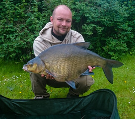 Lucky and happy angler holding a Large Bream caught while fishing. Record size bream.
