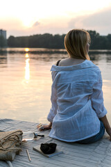 Young woman is resting in the evening by the lake.