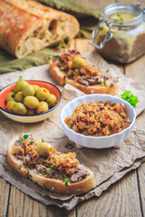 Fresh homemade chicken liver pate on ciabatta bread with roasted onions and olives
