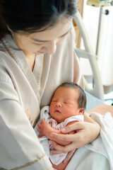 Asian mother with newborn baby in the hospital. New born baby boy resting in mothers arms. A beautiful moment little cute newborn baby in her mother's arm in a hospital.