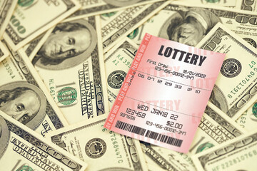 Red lottery ticket lies on big amount of hundred dollar bills. Lottery playing concept or gambling addiction. Close up