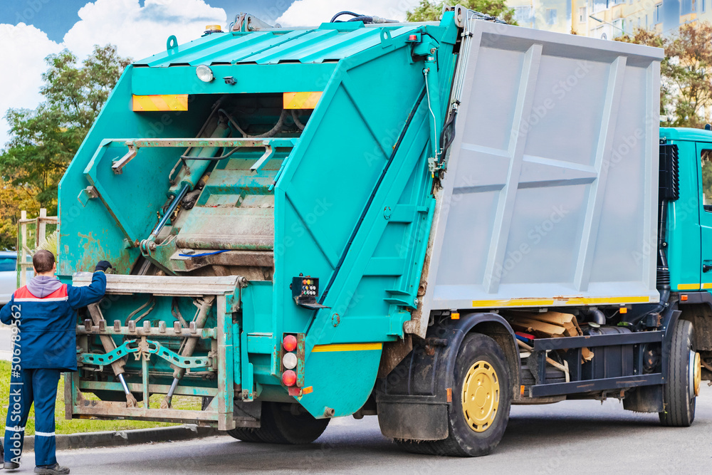 Leinwandbilder A garbage truck picks up garbage in a residential area. Loading mussar in containers into the car. Separate collection and disposal of garbage. Garbage collection vehicle.