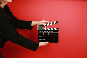 hand holding movie clapper on red background