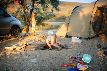 funny child on rug does exercises near the tents, rest as savages with children and tents,...