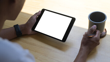 Over older few of man drinking coffee and surfing internet on digital table at home