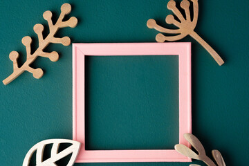 pink pastel photo frame with wooden leaf on green table