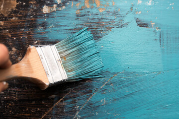 Close up paintbrush in hand and painting on the wooden table.