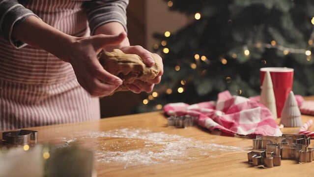 Merry Christmas, Happy New Year. Gingerbread cooking, cake, biscuit or strudel baking. Woman in apron is kneading, massaging dough. Girl gently holding, creases dough. Christmas decorations at kitchen