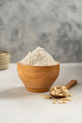 Oat wholegrain flour in wooden bowl. Gluten - free flour concept.