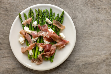 Green asparagus with mozzarella cheese and prosciutto ham. Seasonal delicious food. keto dietary lunch or dinner.