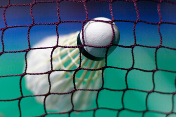 The shuttlecock is floating in a green badminton court net. background shot in low light	