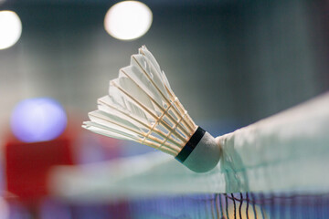 The shuttlecock is floating in a green badminton court net. background shot in low light	