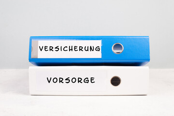 Two folders with the  words insurance and precaution in german langauge, documents at an office,...