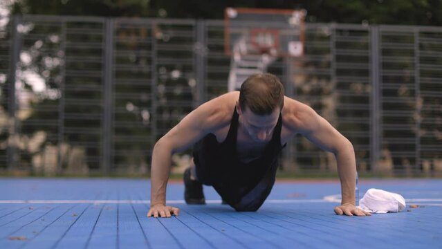 Fit young caucasian man working out on crossfit strength training doing push ups at the calisthenics park. Man standing in plank pose on rug. Concept of health, meditation, fitness, ad
