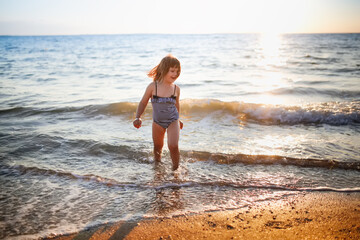 European girl child alone on the seashore, wide angle shooting, vacation with children at sea