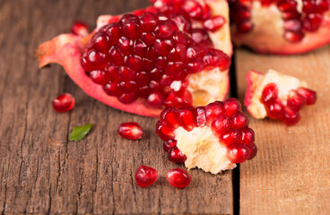 Juicy pomegranate and its half Beautiful composition with juicy pomegranates, on old wooden table