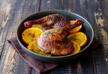 Baked duck legs with oranges and rosemary. Rustic style.