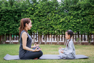 Family Asian Mother teacher training yoga child daughter on a yoga mat at home garden