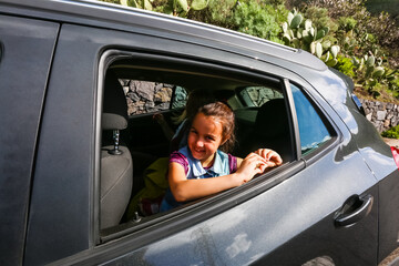 Little fun girl speeds in car near the open window