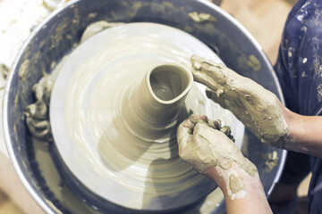 Pottery workshop. Female ceramic artist molding clay at pottery wheel. Close up view. Creative handmade craft. 