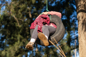Young girl on tire swing in the backyard swinging back and forth having fun