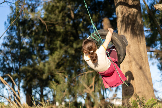 Young girl on tire swing in the backyard swinging back and forth having fun