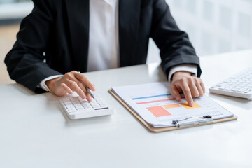 Close-up of business woman hands check company finances and earnings and budget with graph on desk in the office.