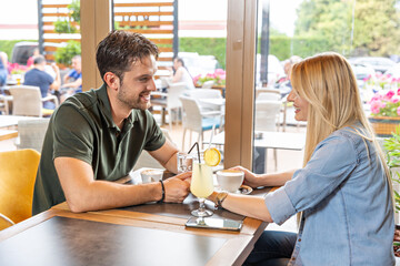 Happy romantic couple sitting in a cafe bar, talking