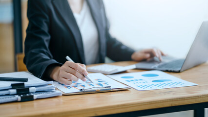 Close-up of business woman hands check company finances and earnings and budget with graph on desk...