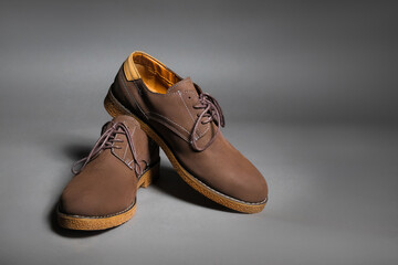 Brown suede shoes with laces on a grey background with copy space